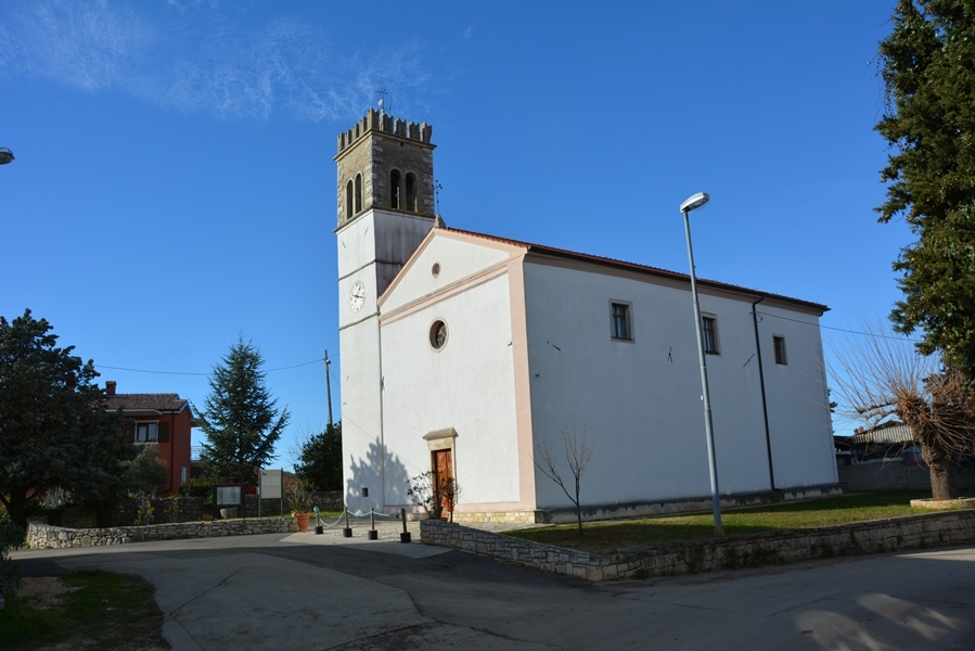 Na slici je župna crkva Svetog Mihovila, u centru naselja Nova Vas. Iza nje se vidi plavo nebo a ispred je asfaltirana cesta.