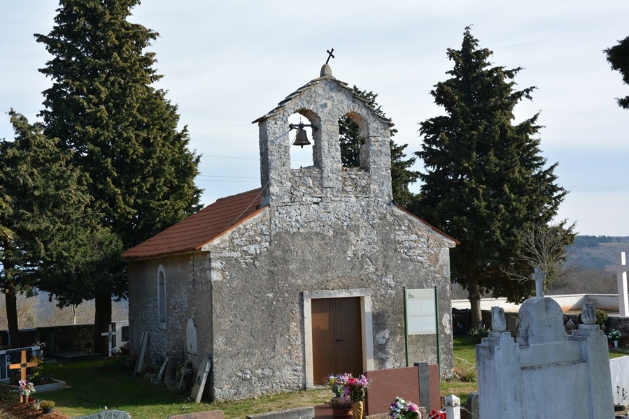 Na slici je crkva Svetog Mihovila Arhanđea, na mjesnom groblju u naselju Srbani. Sa lijeve i desne strane vide se dva visoka čempresa a ispred crkvice vide se grobnice.